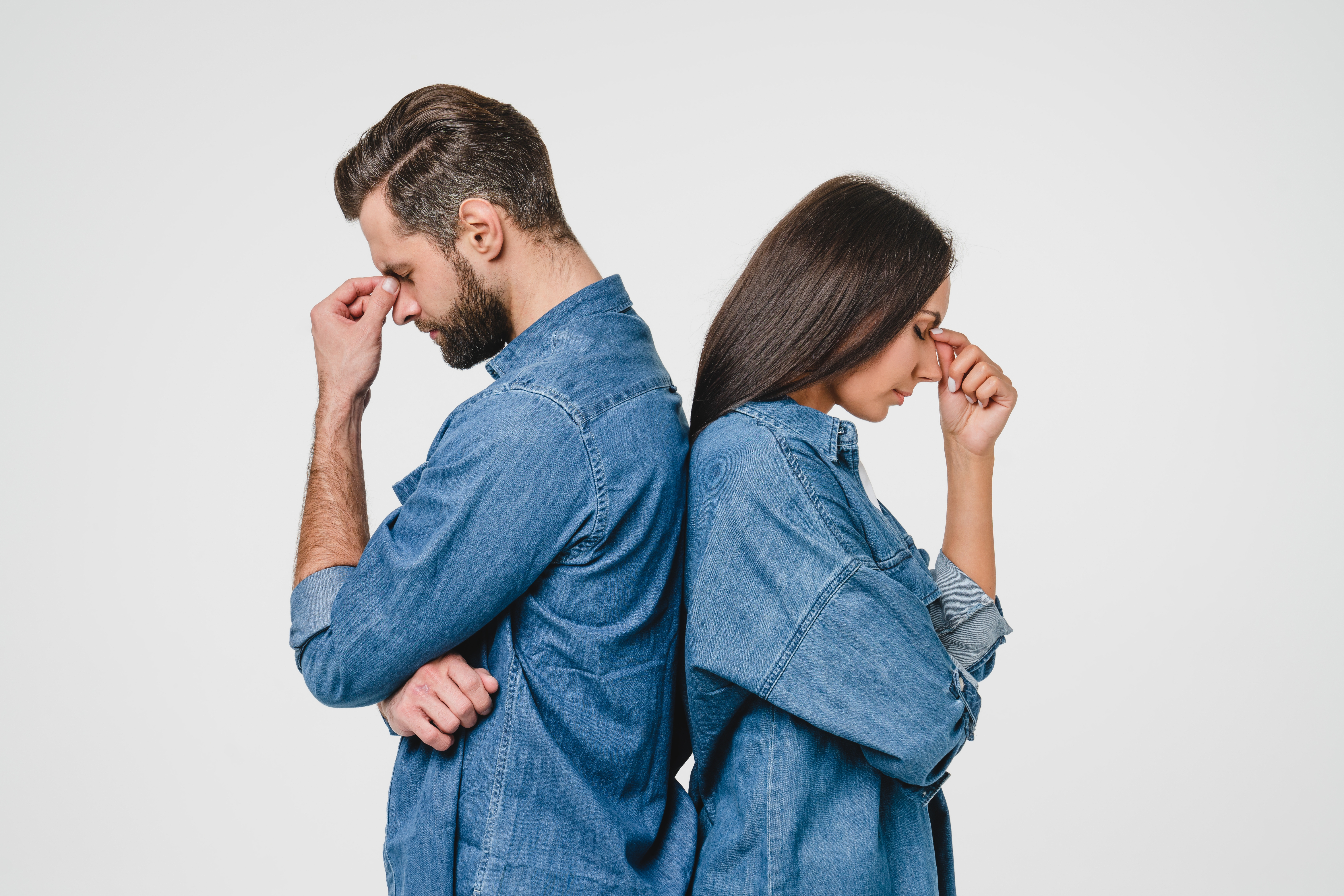 A man and woman standing back to back with their heads in their hands | Source: Shutterstock